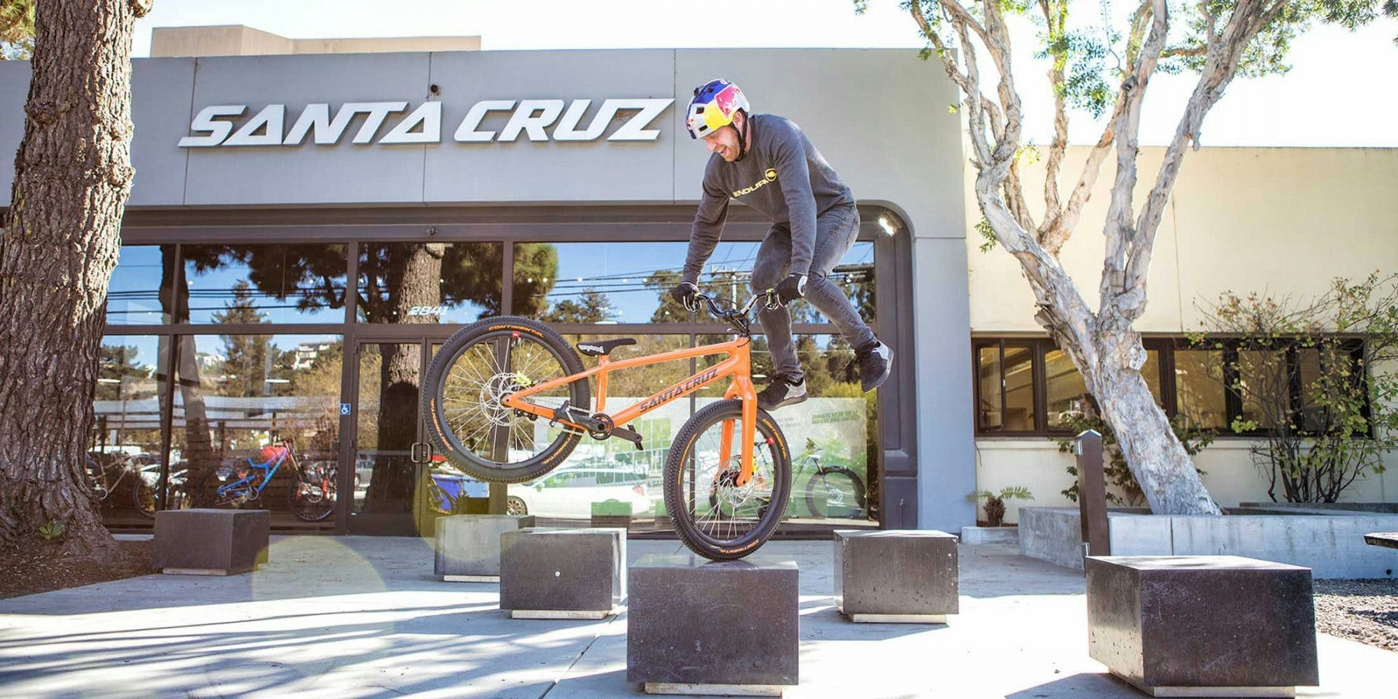 Danny Macaskill on his orange carbon trials bicycle in front of the Santa Cruz Bicycles Factory