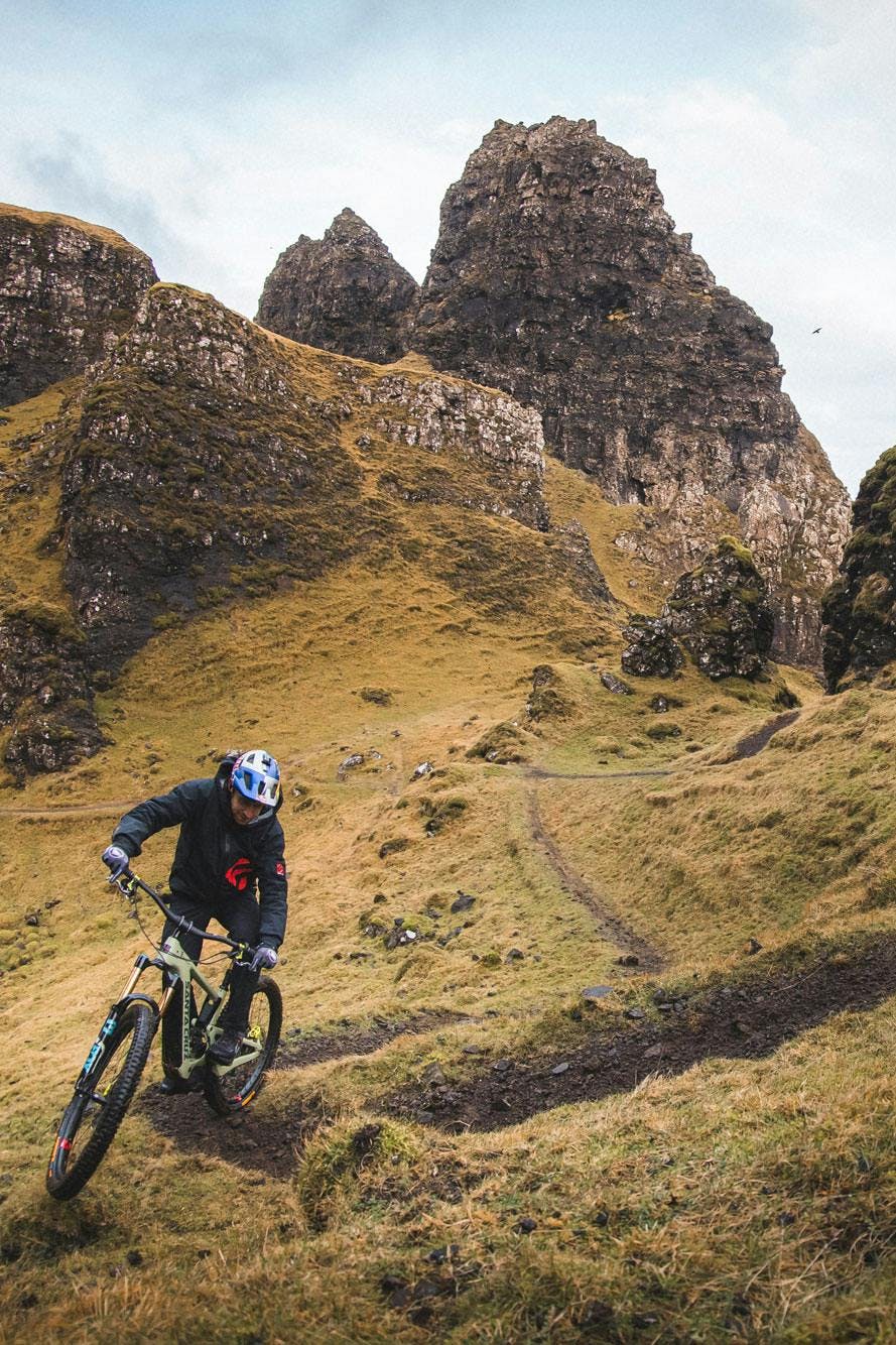 Danny MacAskill riding his Heckler eMTB uphill on a rocky singletrack trail 