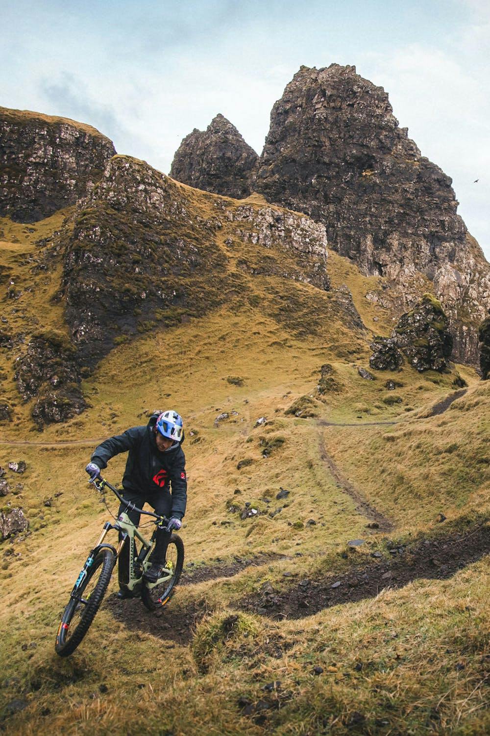 Danny MacAskill riding his Heckler eMTB uphill on a rocky singletrack trail 