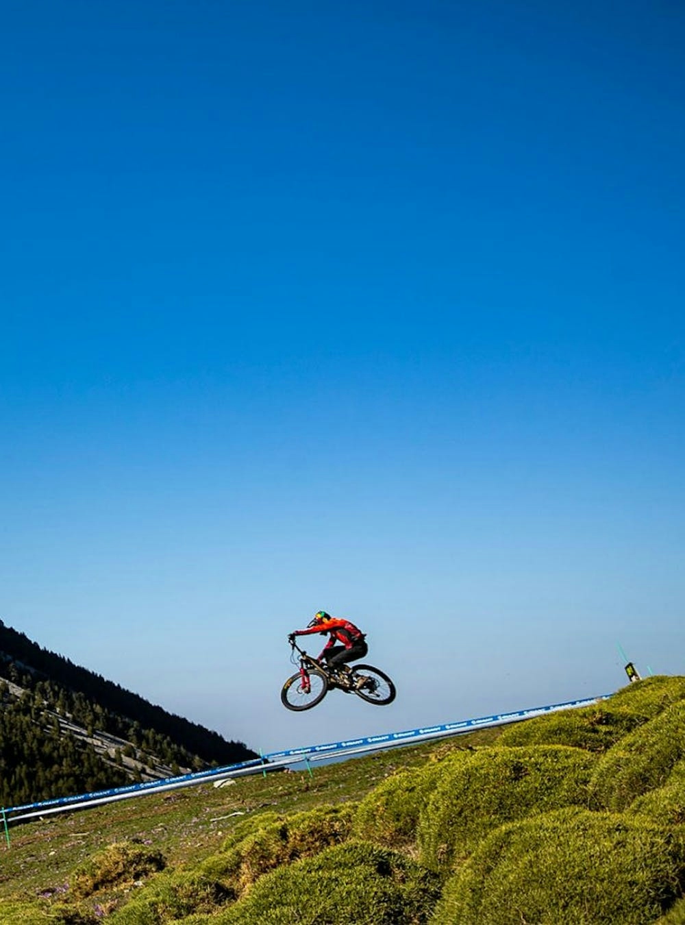 A mountain biker jumping on a bike between a race course