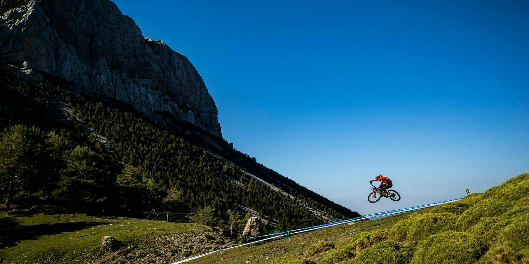 A mountain biker jumping on a bike between a race course