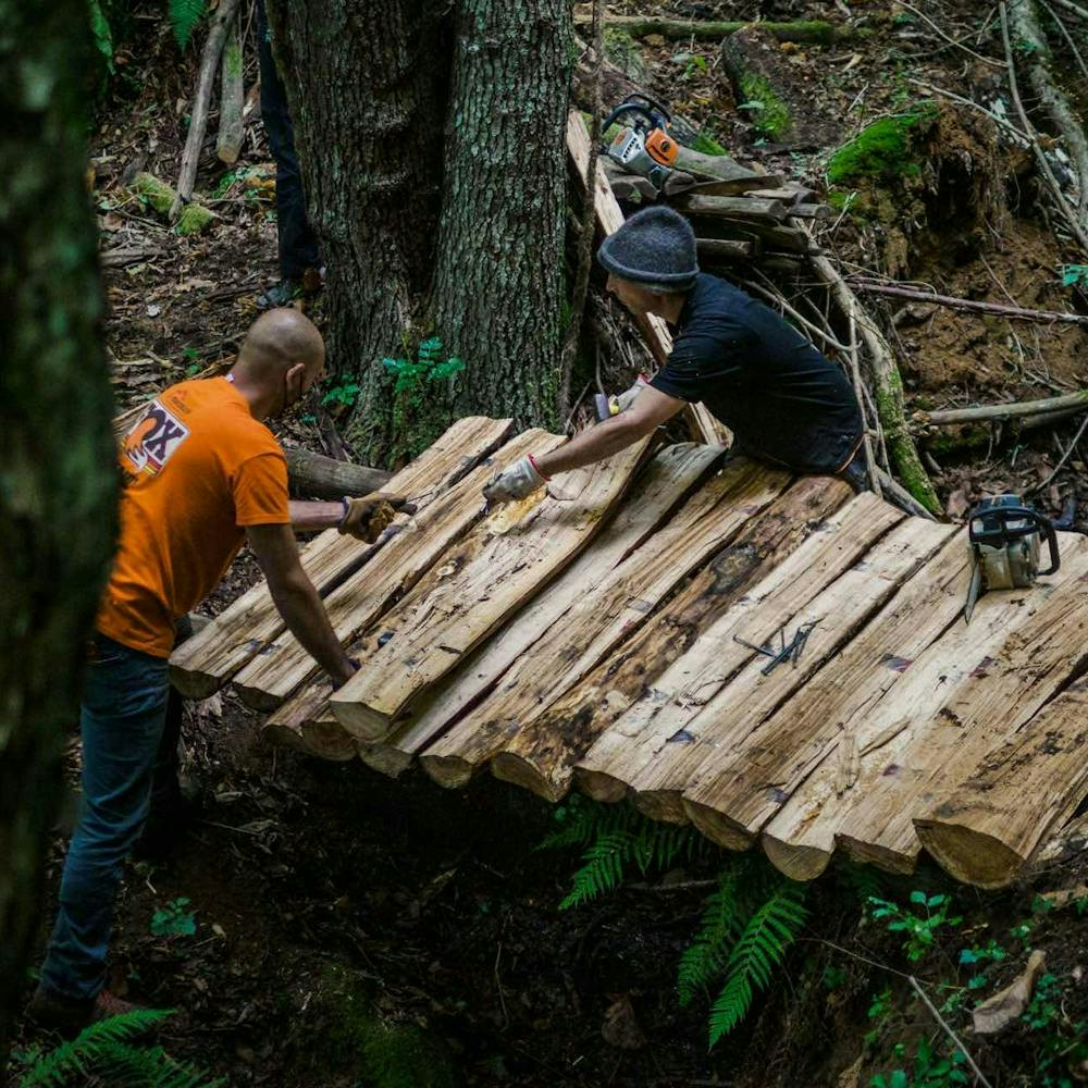 Two trailbuilders working on a wooden bridge