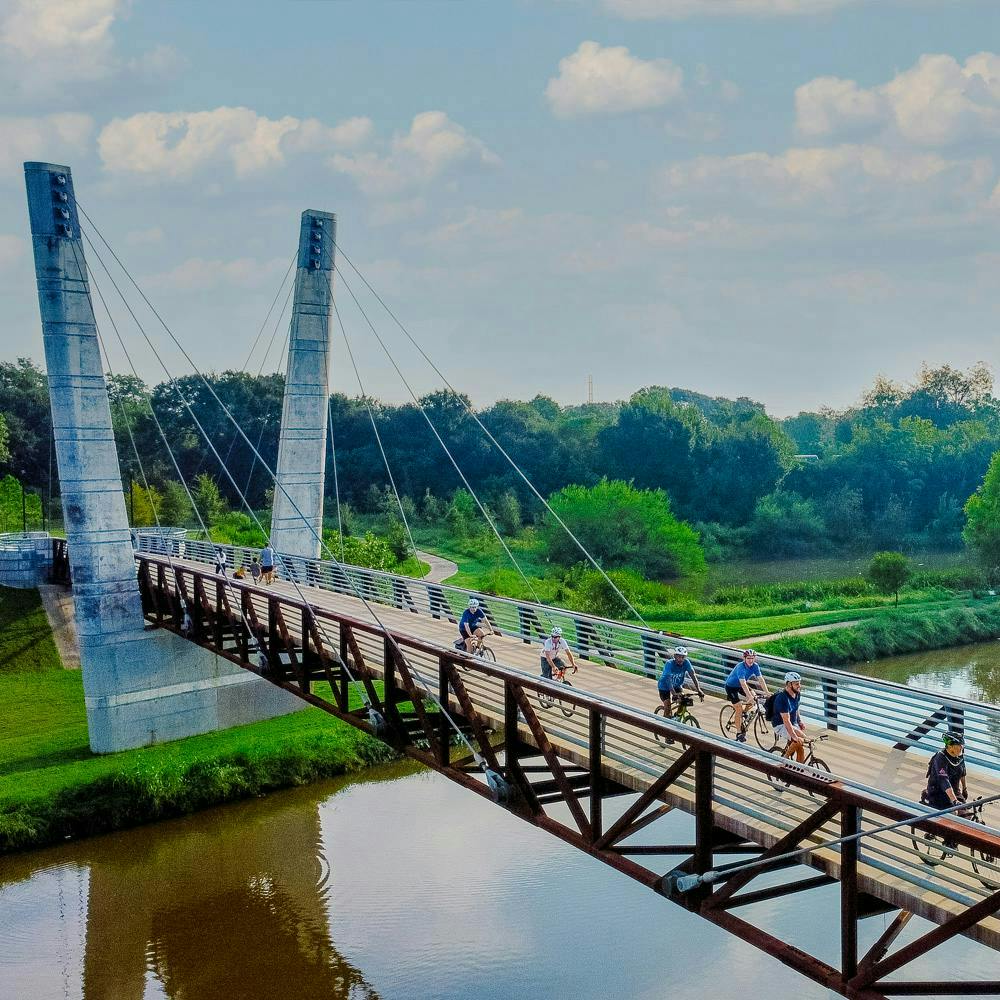A group of cyclists riding over a suspension bridge