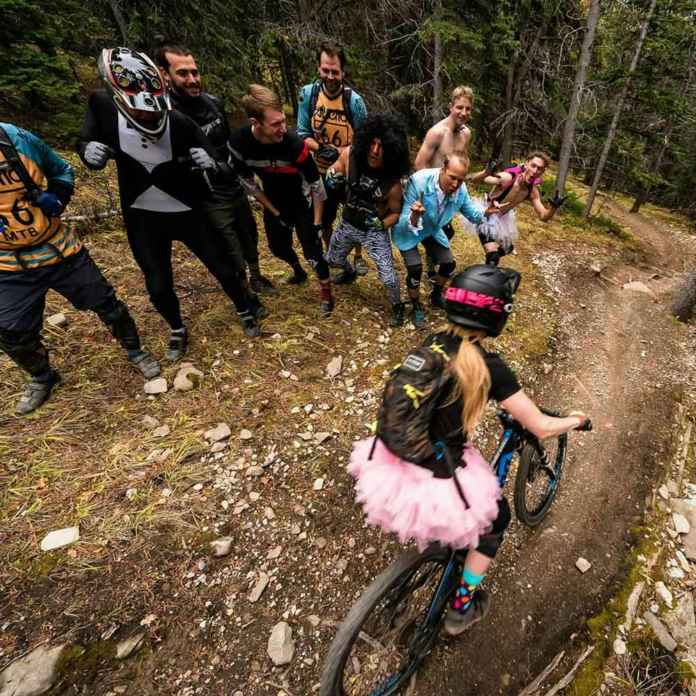 Hecklers cheering on a mountain biker wearing a pink dress