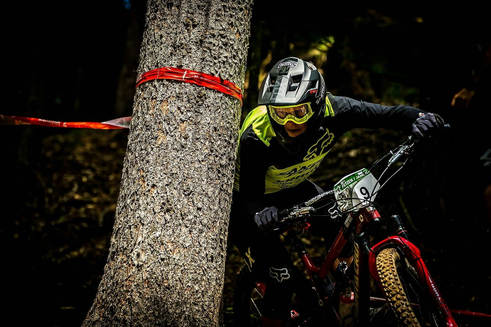 A mountain biker cornering around a tree