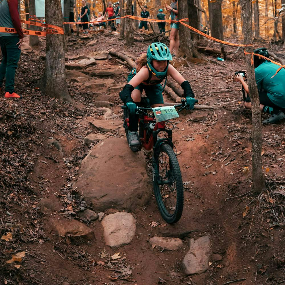 A mountain biker racing down a rocky section of singletrack trail