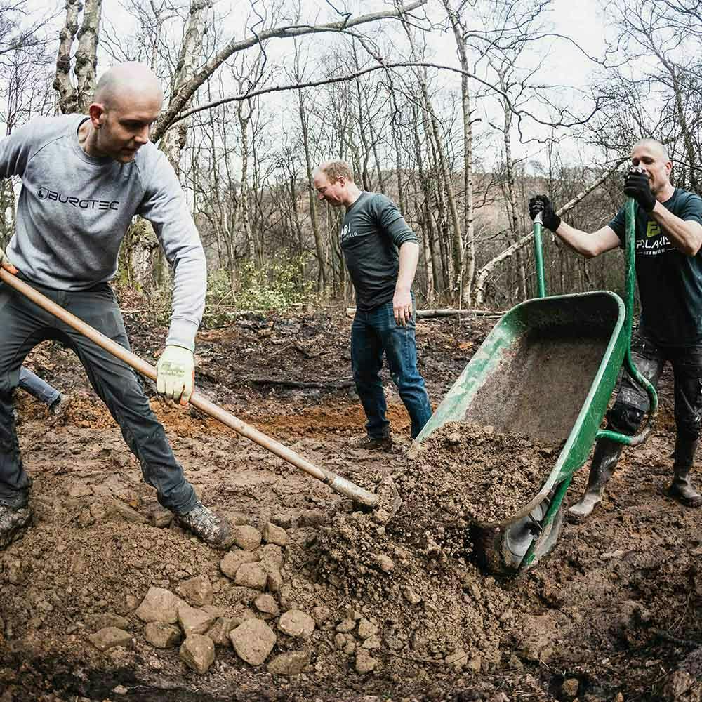 Trail builders moving dirt out of a wheelbarrow 