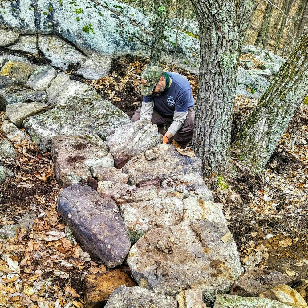 A trail builder repositioning a rock roll