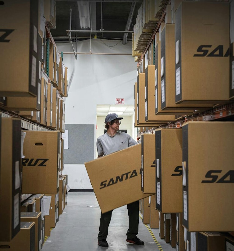 A factory worker pulling out a Santa Cruz Bike Box off of a shelf filled with other boxes