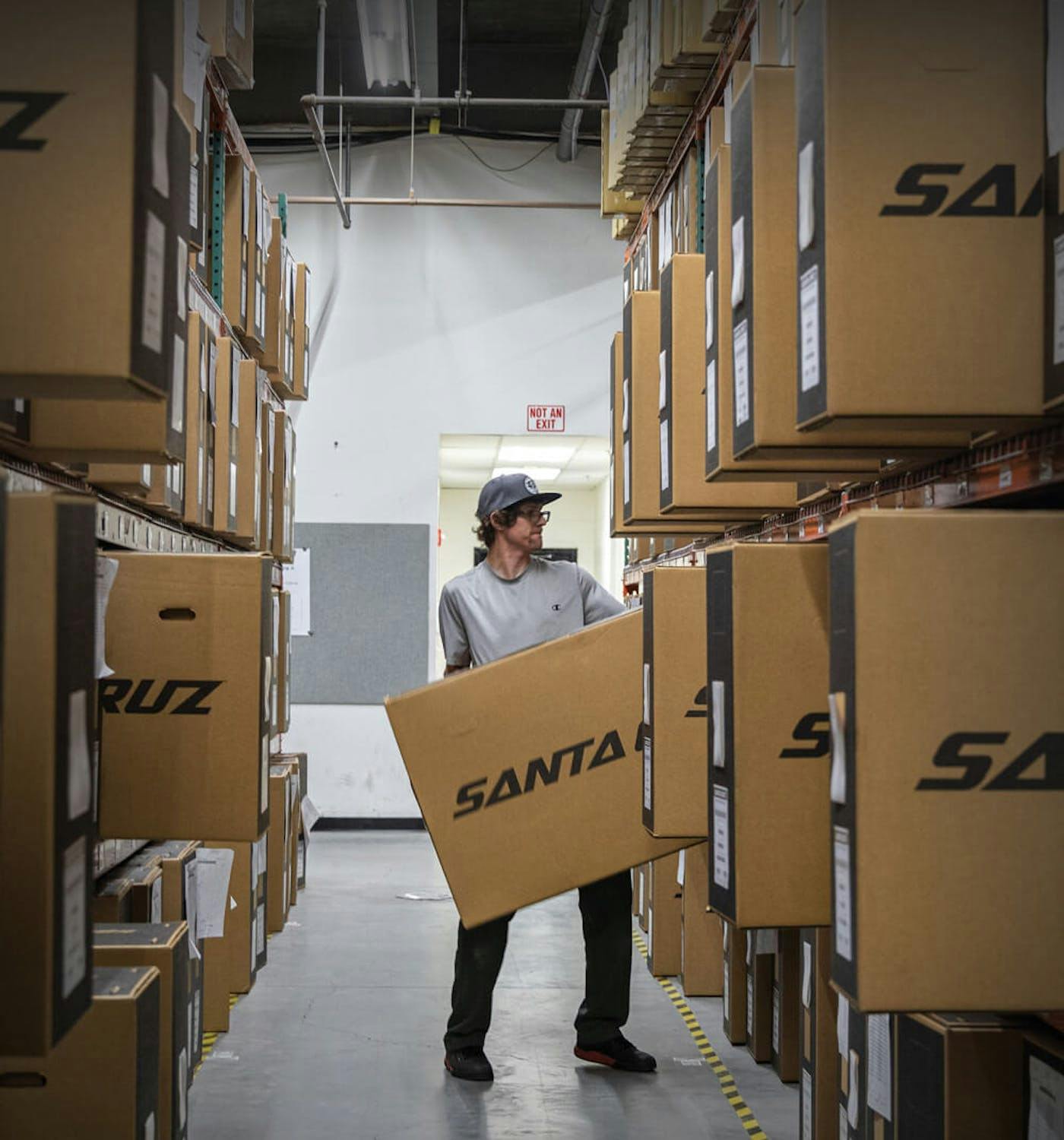 A factory worker pulling out a Santa Cruz Bike Box off of a shelf filled with other boxes