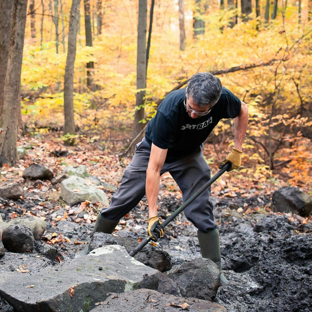 A trail builder moving a rock 