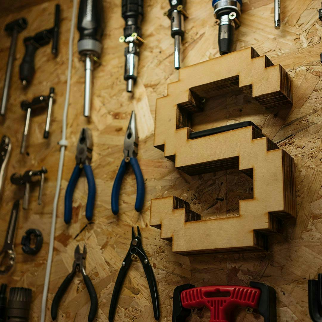 A wall with hanging tools and a hanging wooden S
