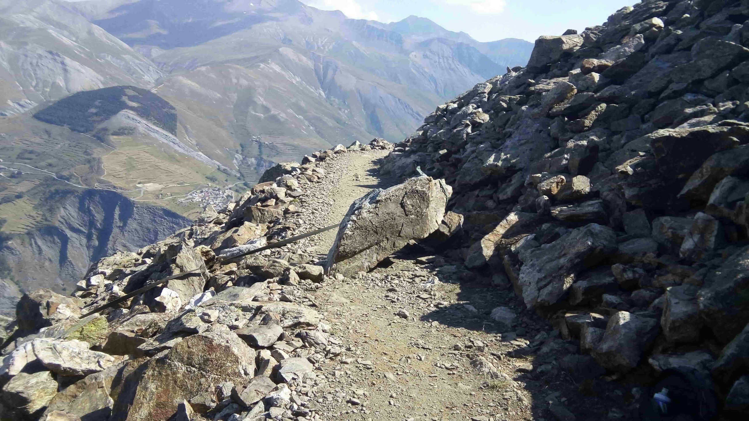 A rocky section of trail in La Grave with larger mountains in the background