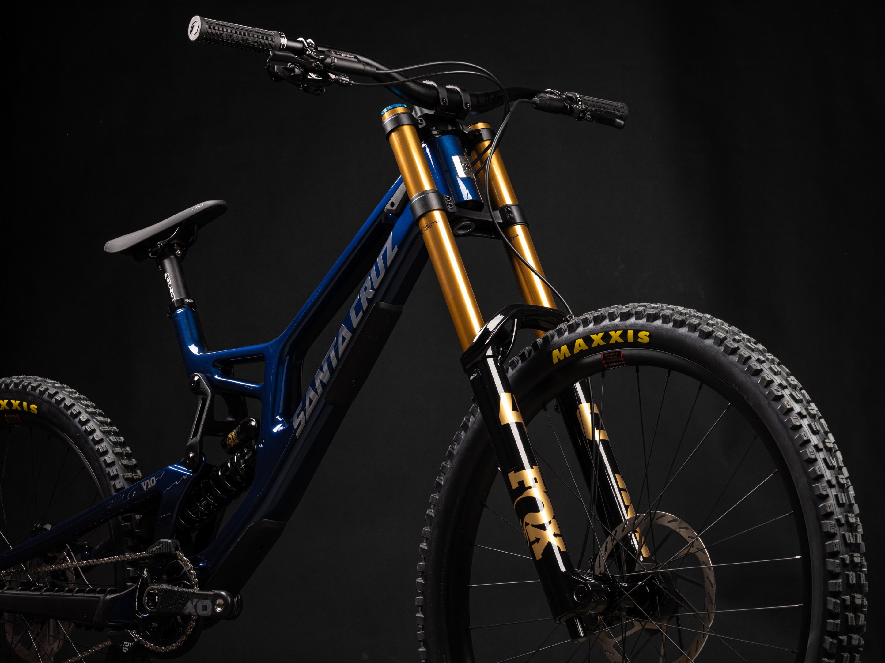 Mountain bike with blue frame and gold suspension fork on a black background