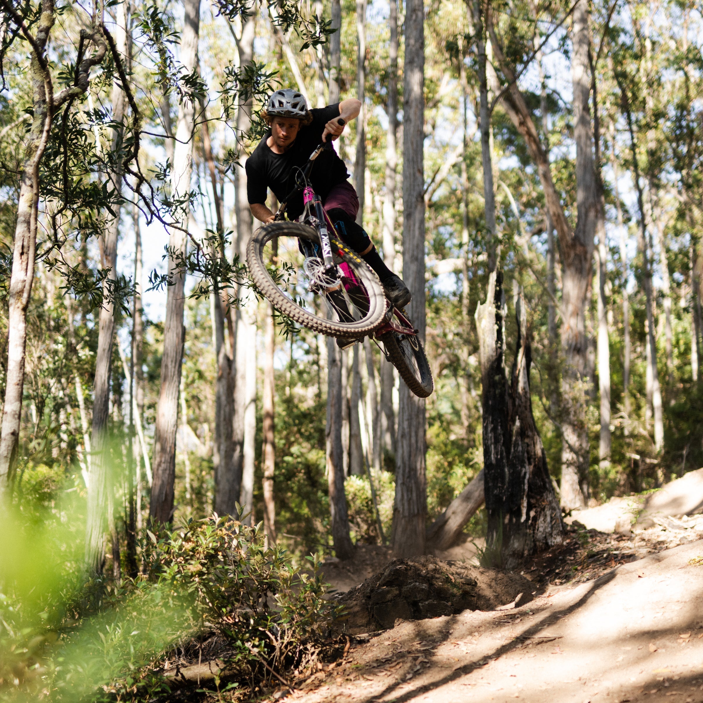 Person on a mountain bike performing a jump in a forest setting