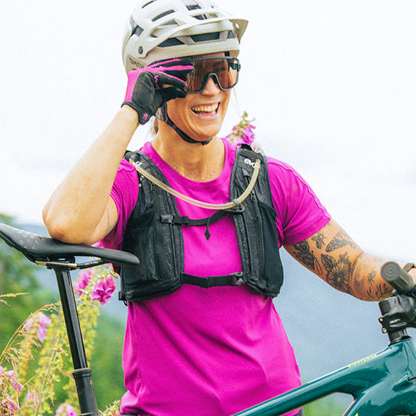 Person on a bicycle wearing a pink shirt and helmet in a natural setting