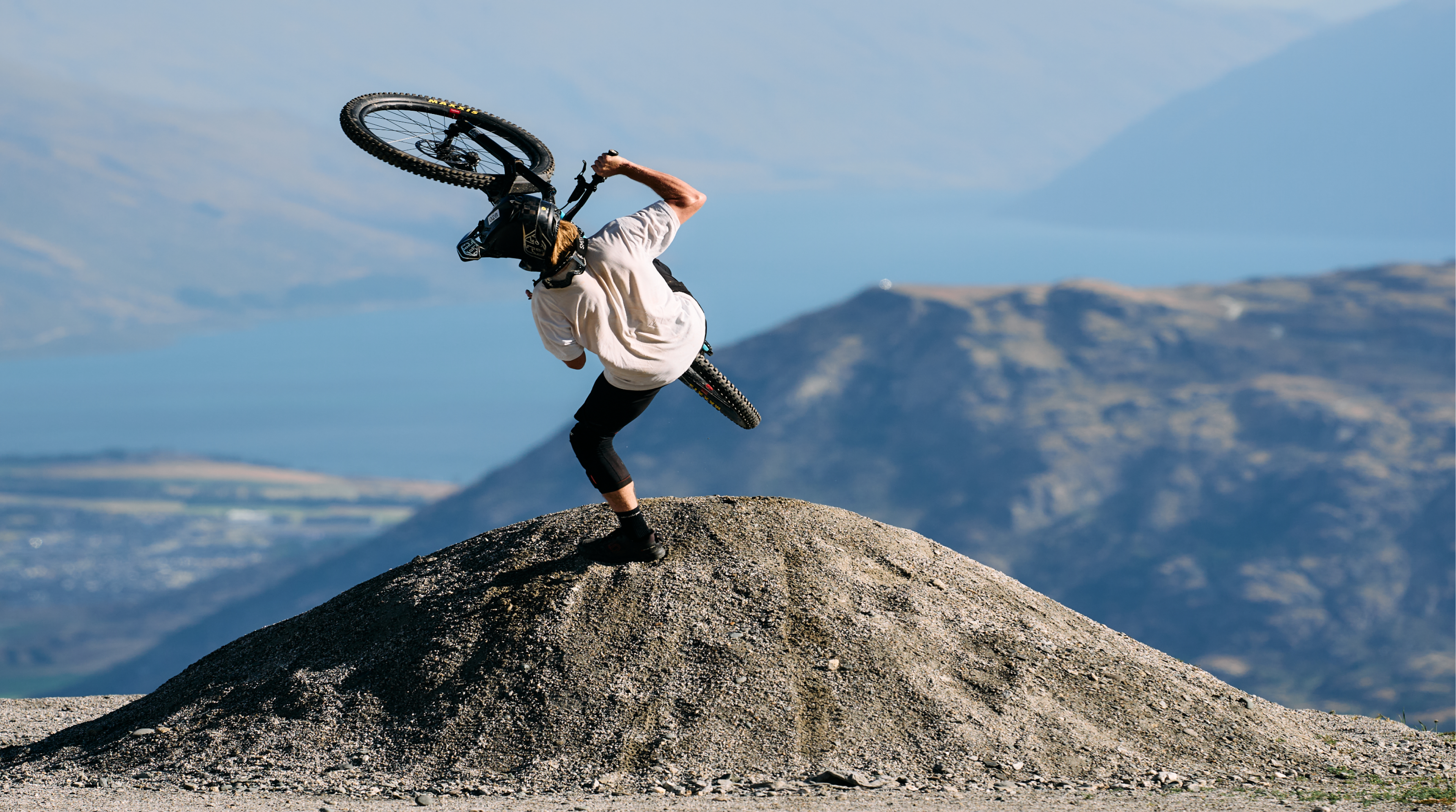 Person performing a bike trick on a mountain with a scenic background