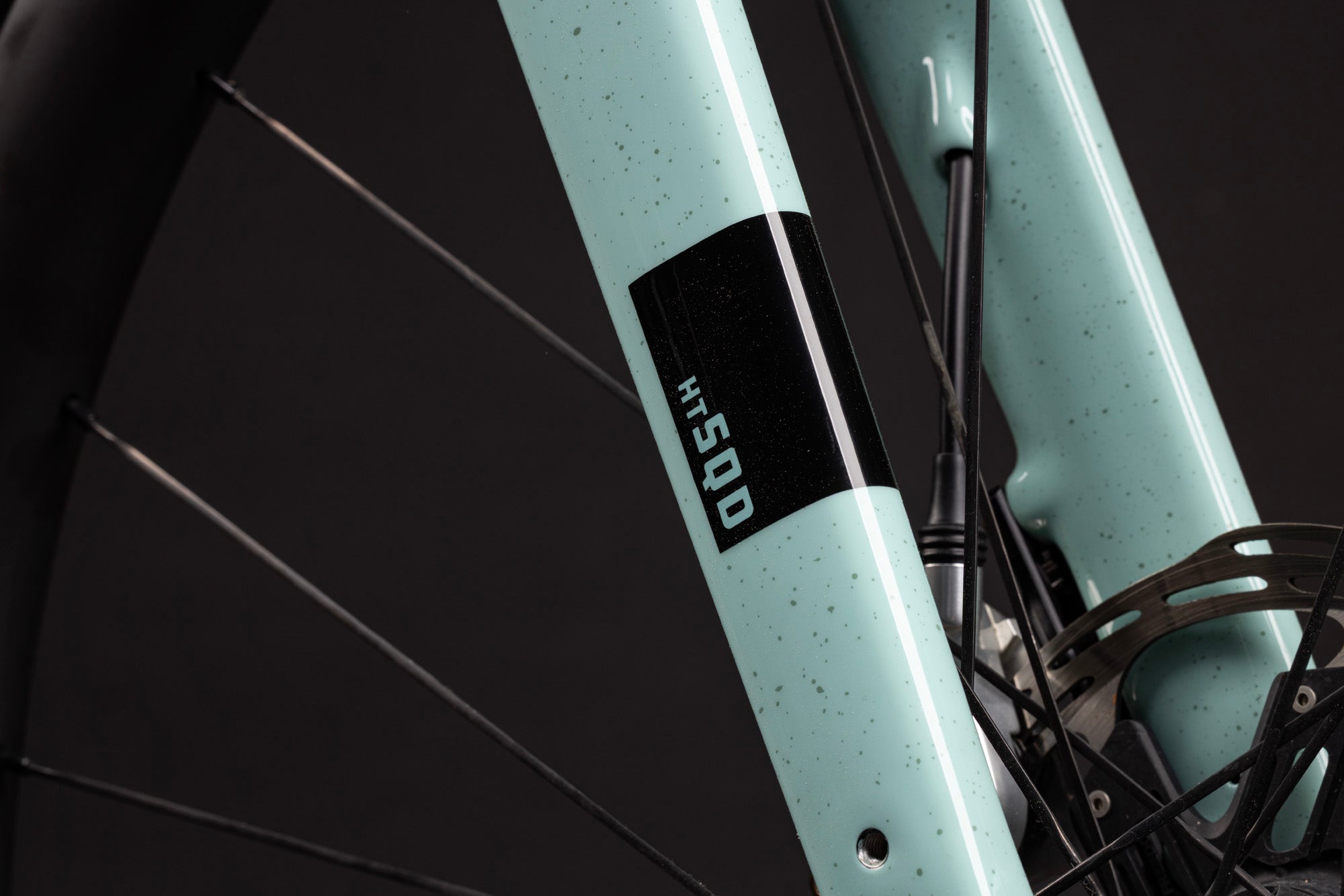 Close-up of a bicycle frame with a brand logo on a dark background