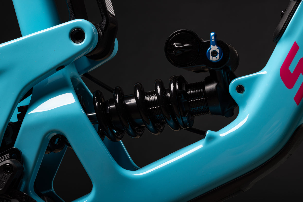 Close-up of a turquoise motorcycle suspension system with visible branding on a black background