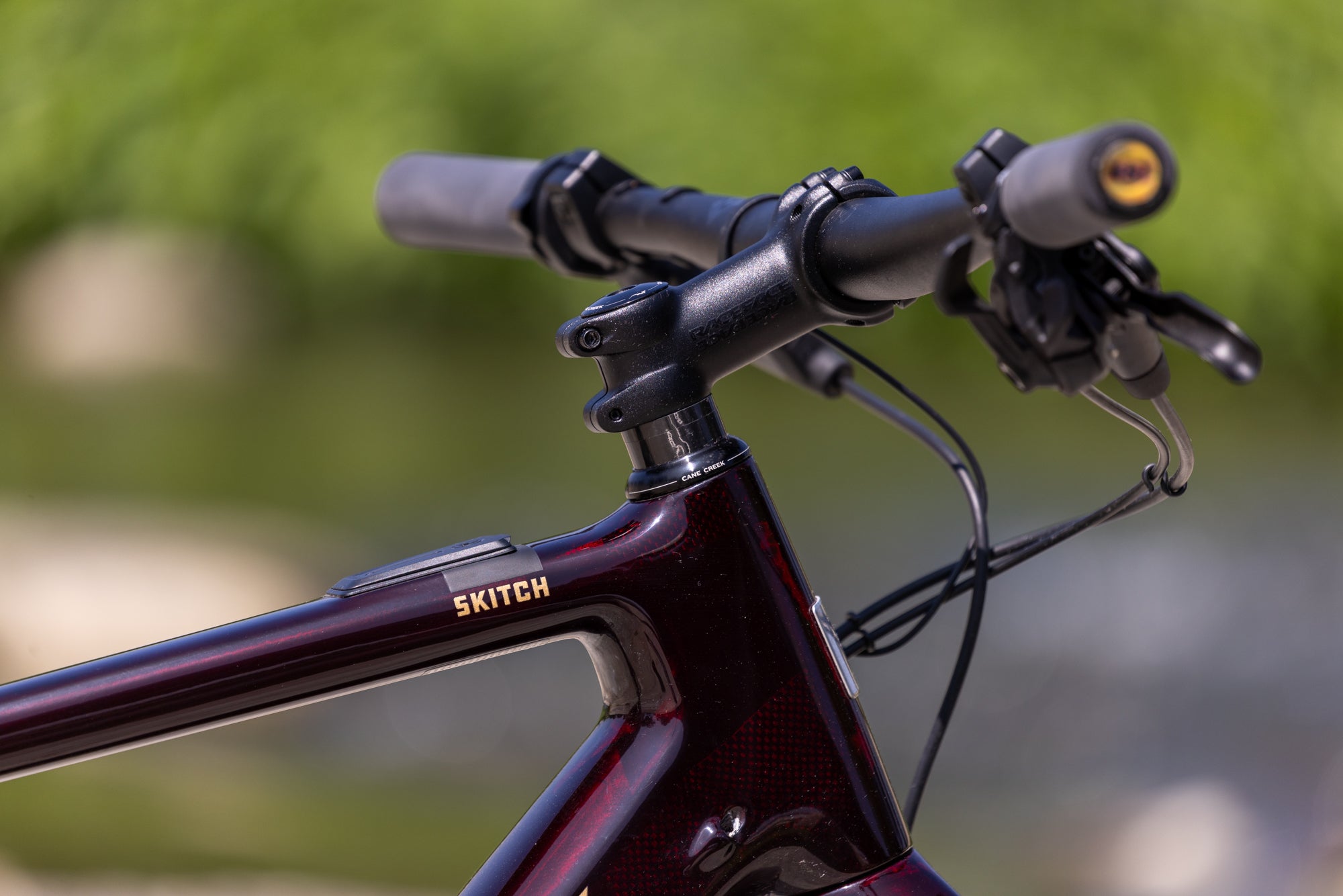 Close-up of a bicycle handlebar with 'SKITCH' branding against a blurred green background